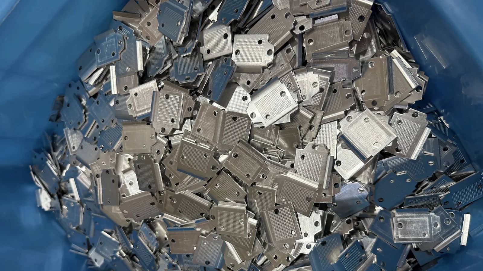 Batch of stamped conductive parts arranged in production bins.