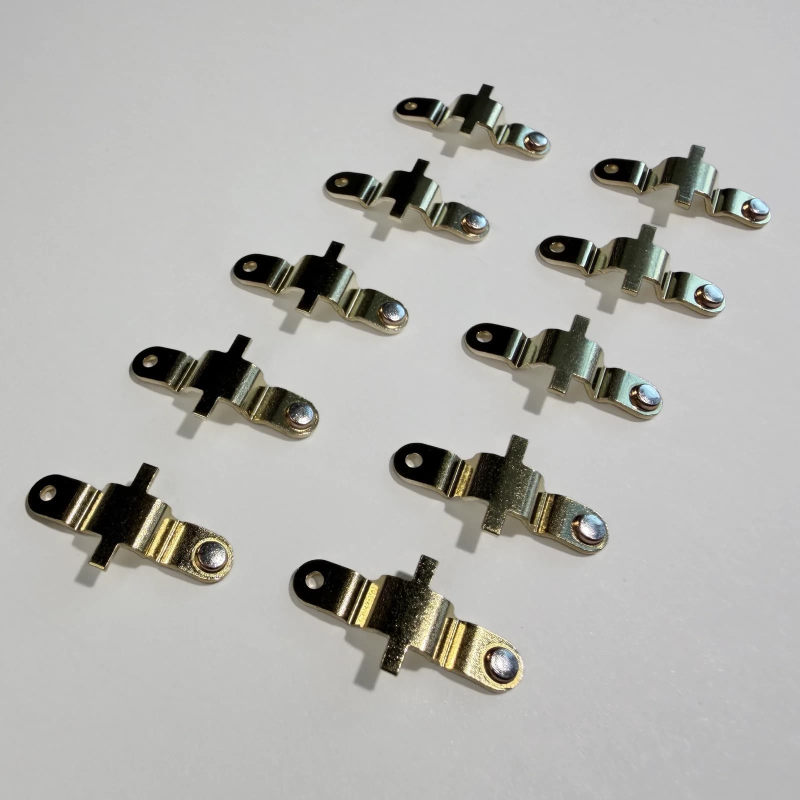 Custom riveted electrical contact assemblies shown on a light neutral background.