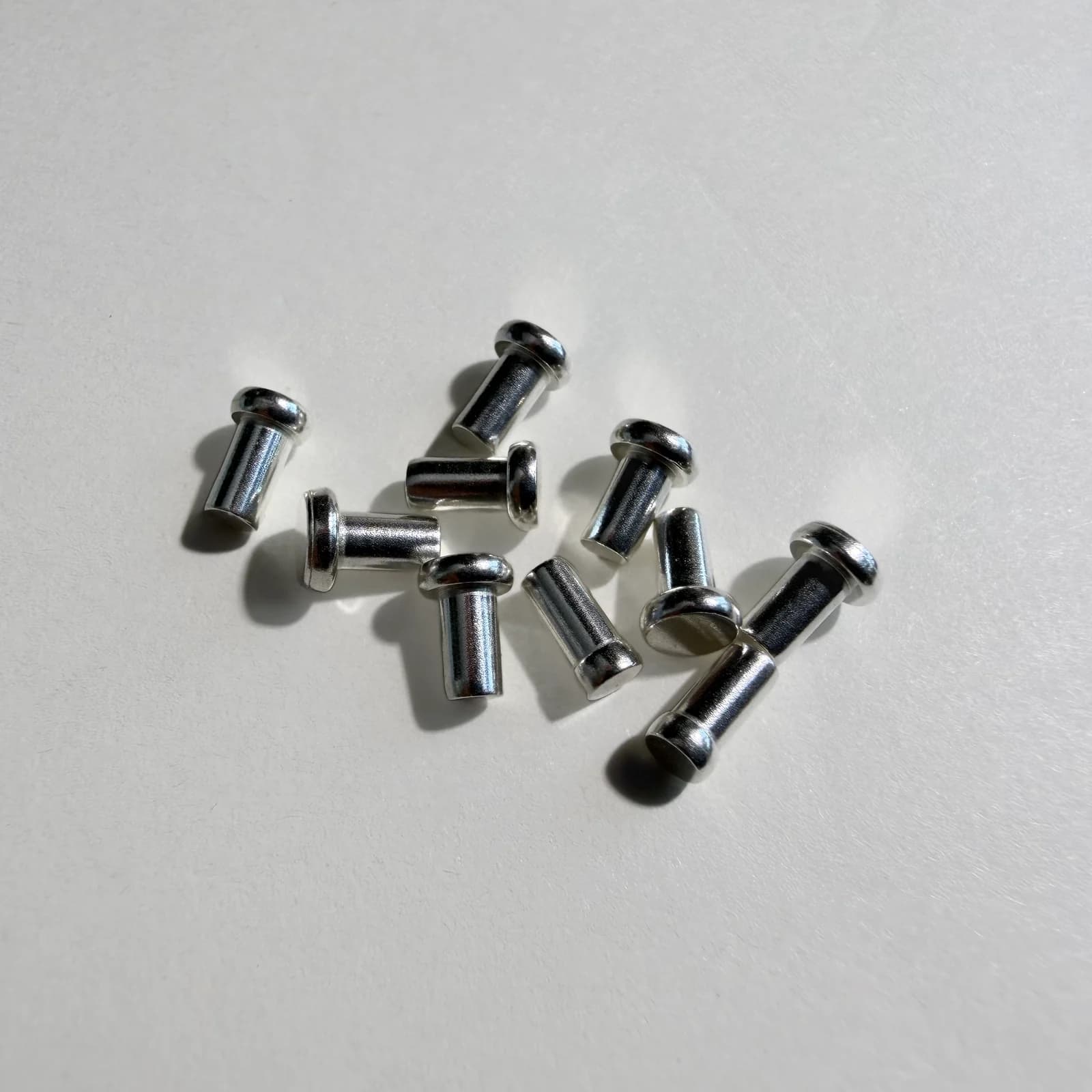 Custom solid electrical contact rivets arranged on a light neutral background.