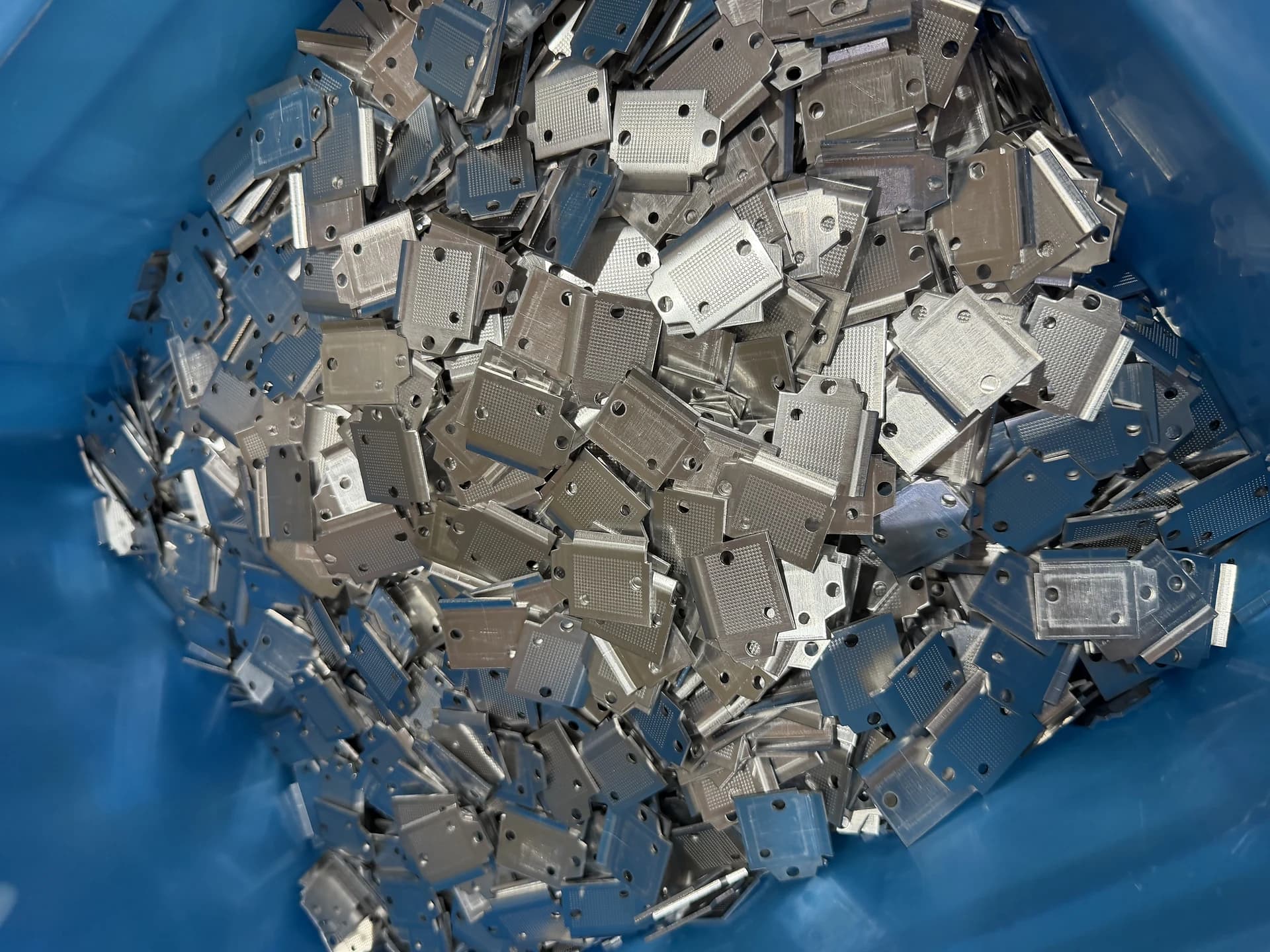 Stamped conductive parts collected in a production container.