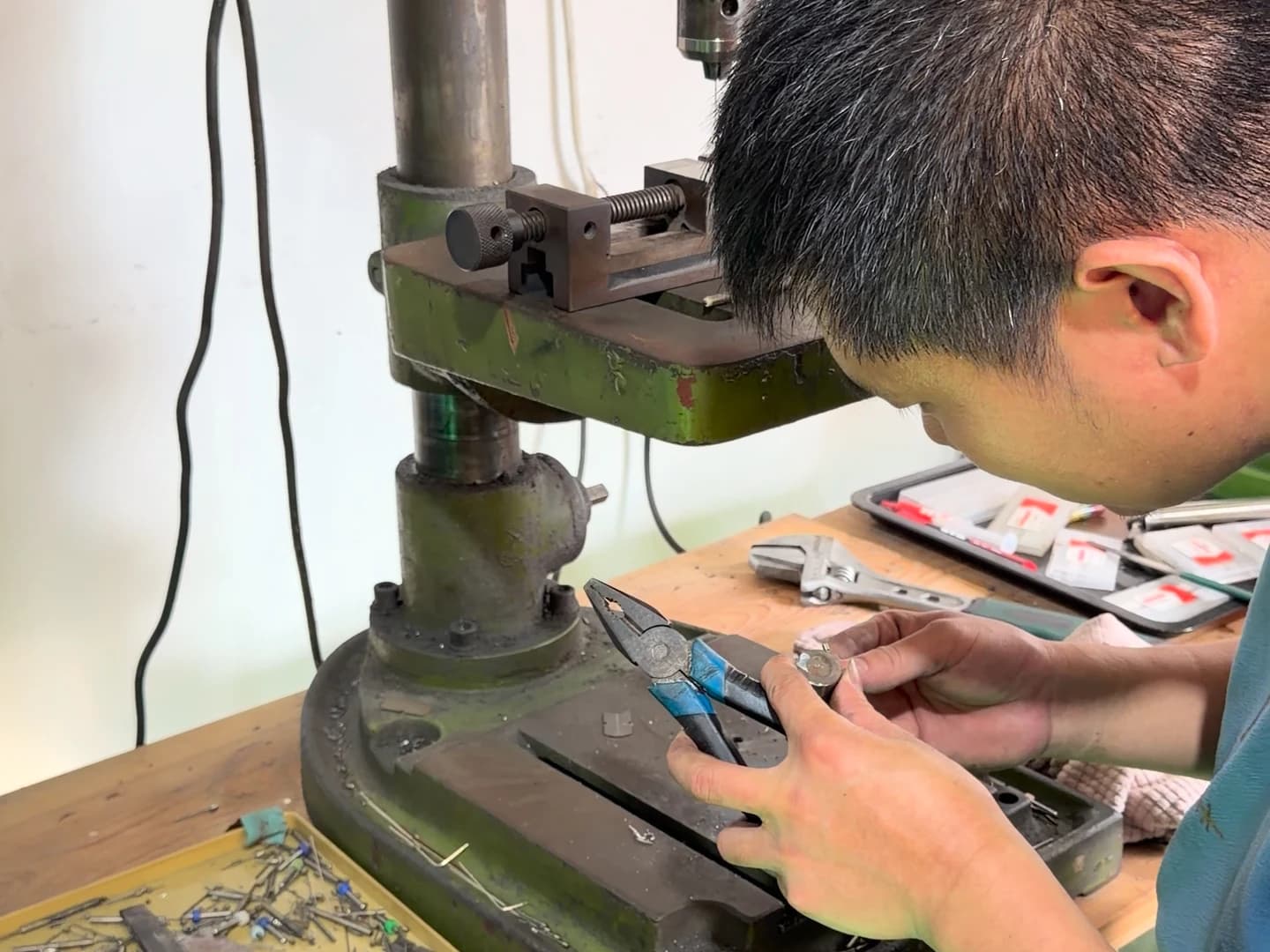 An operator handling a small metal part at a workshop bench.