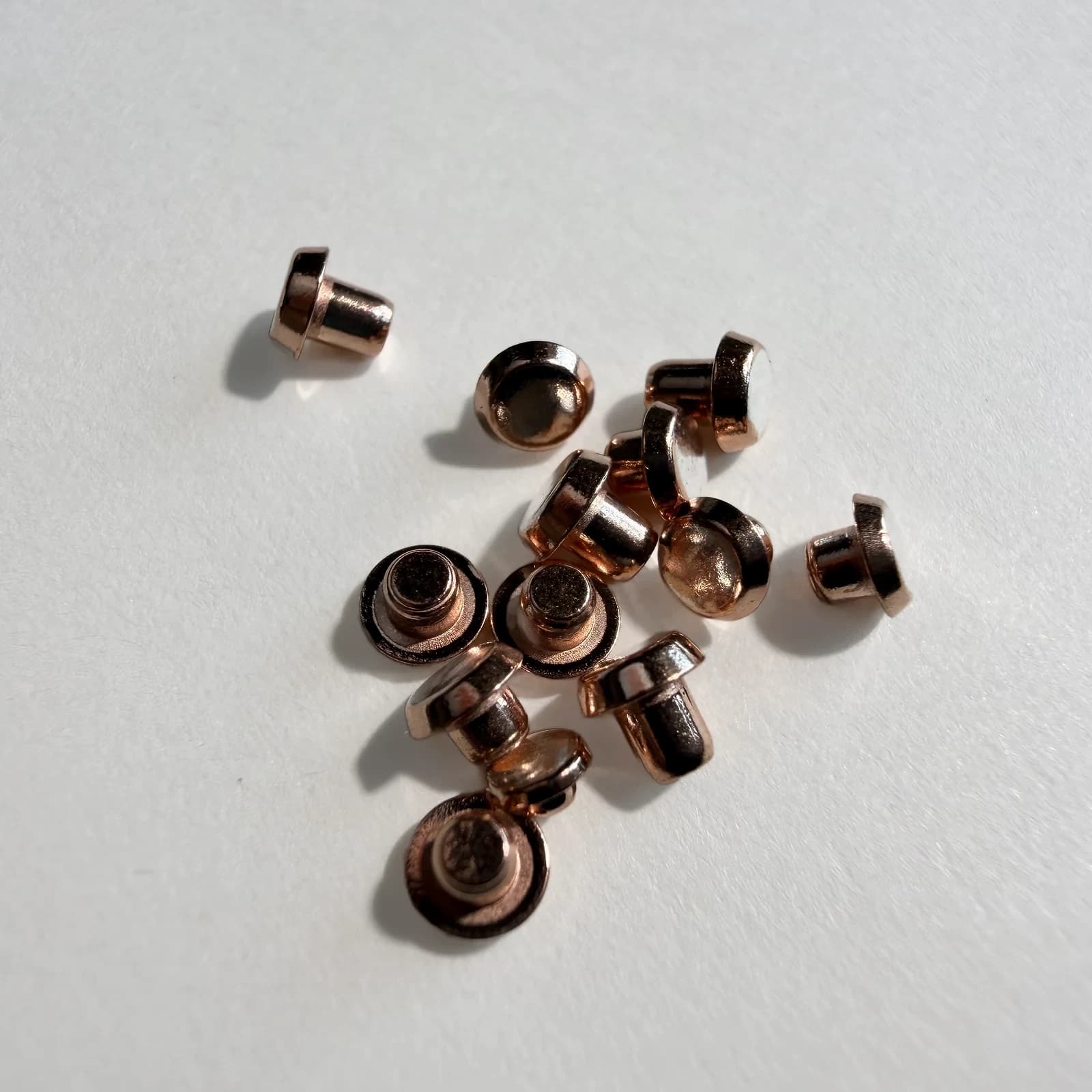 Custom bimetal electrical contact rivets arranged on a light neutral background.