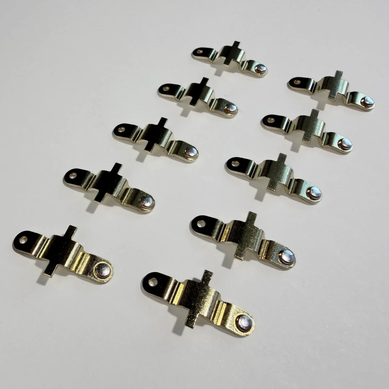 Custom riveted electrical contact assemblies shown on a light neutral background.