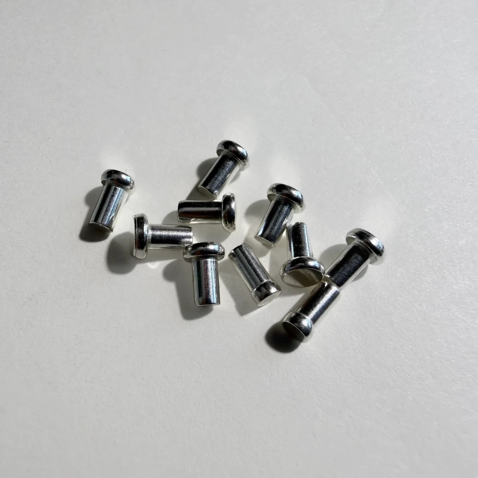 Custom solid electrical contact rivets arranged on a light neutral background.