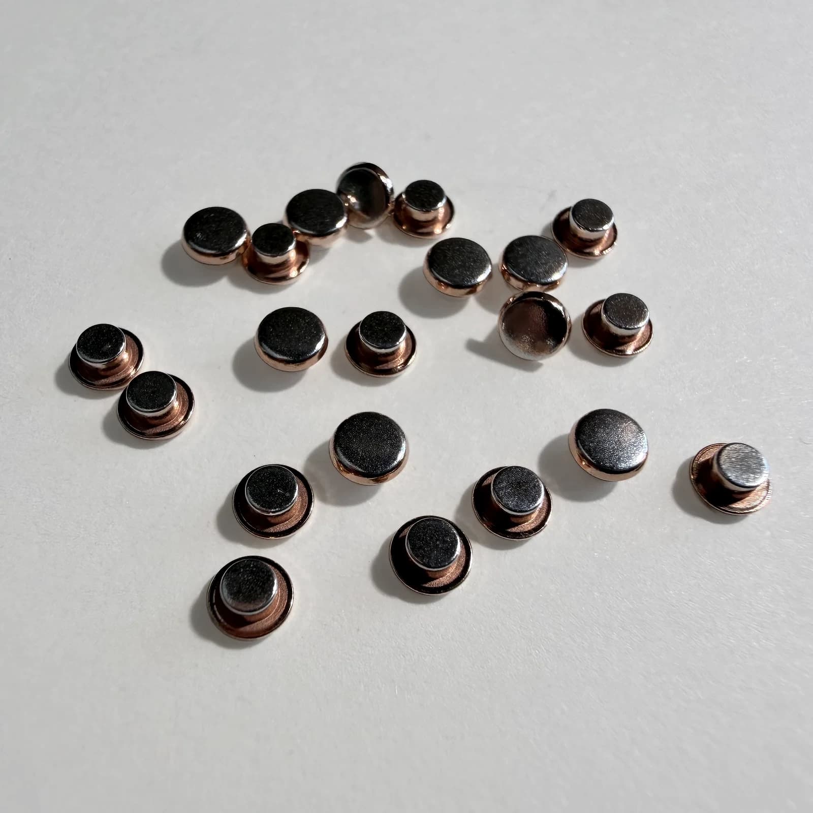 Custom trimetal electrical contact rivets arranged on a light neutral background.
